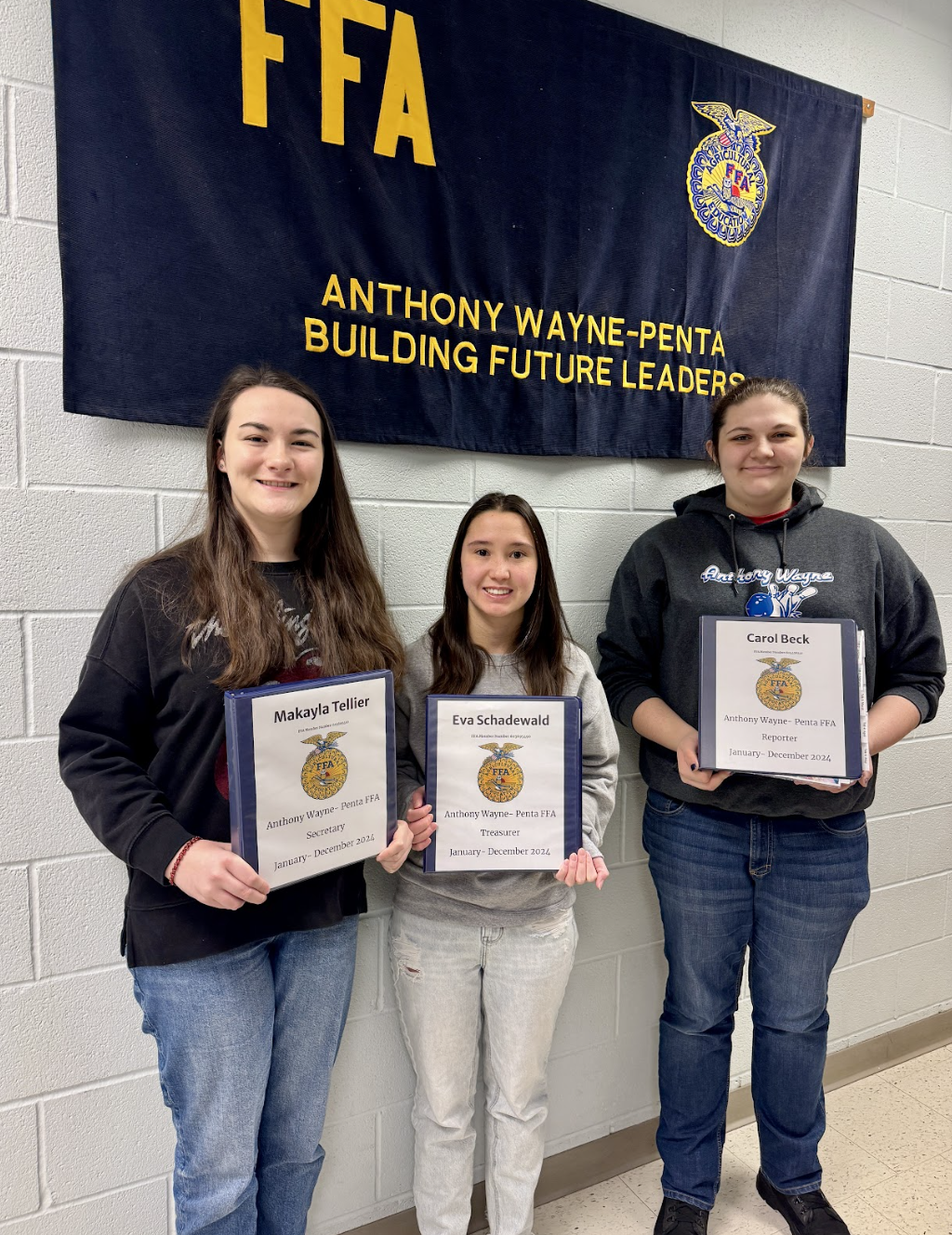 three students show their chapter awards in front of ffa banner