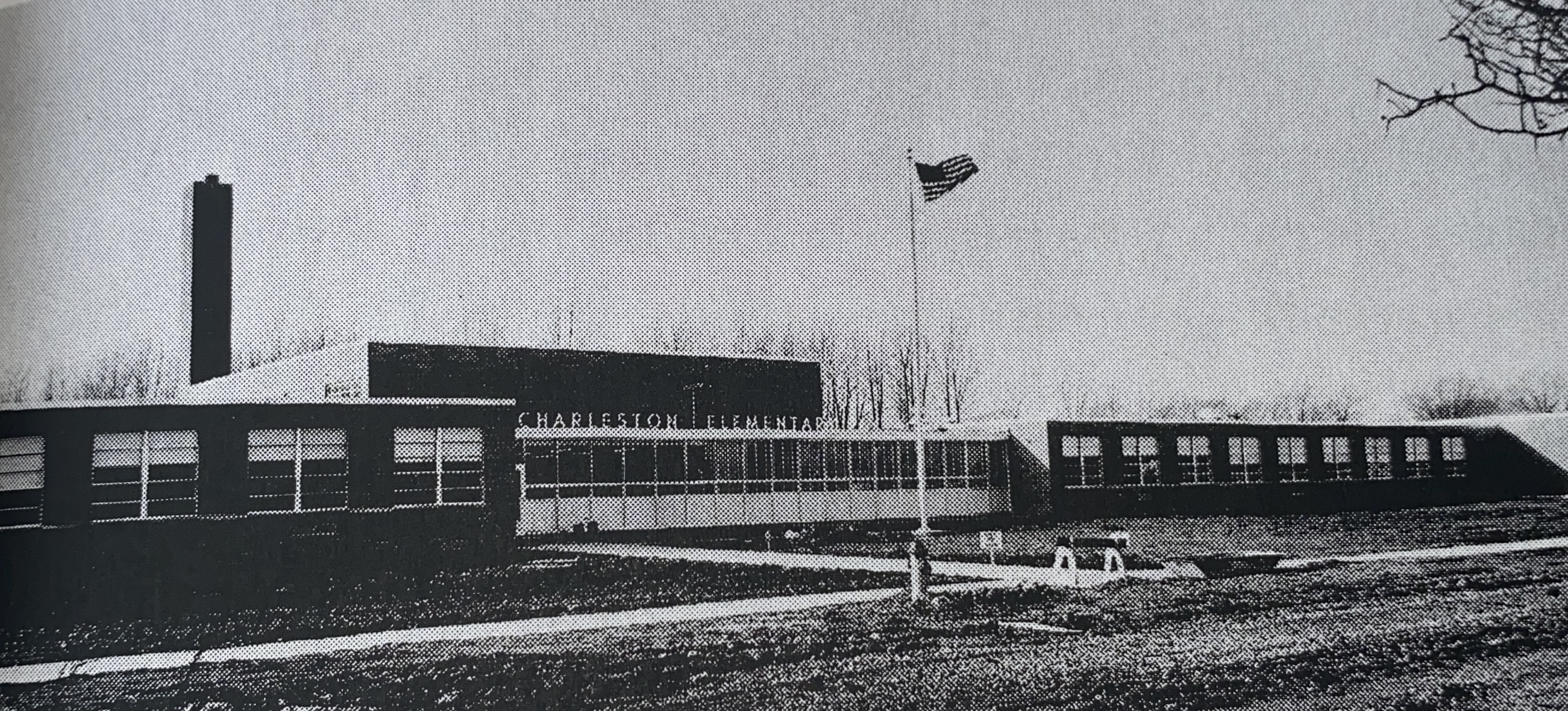 black and white photo of school with flag pole in front