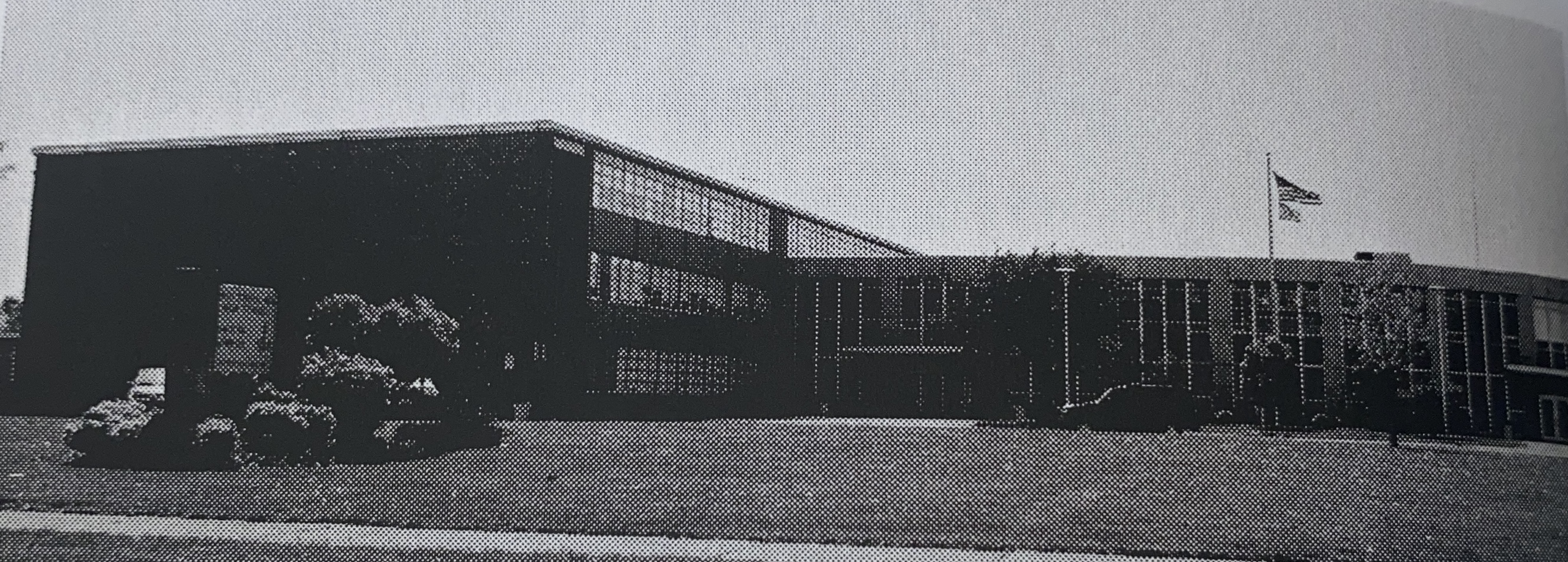 black and white photo of front of building and school sign 