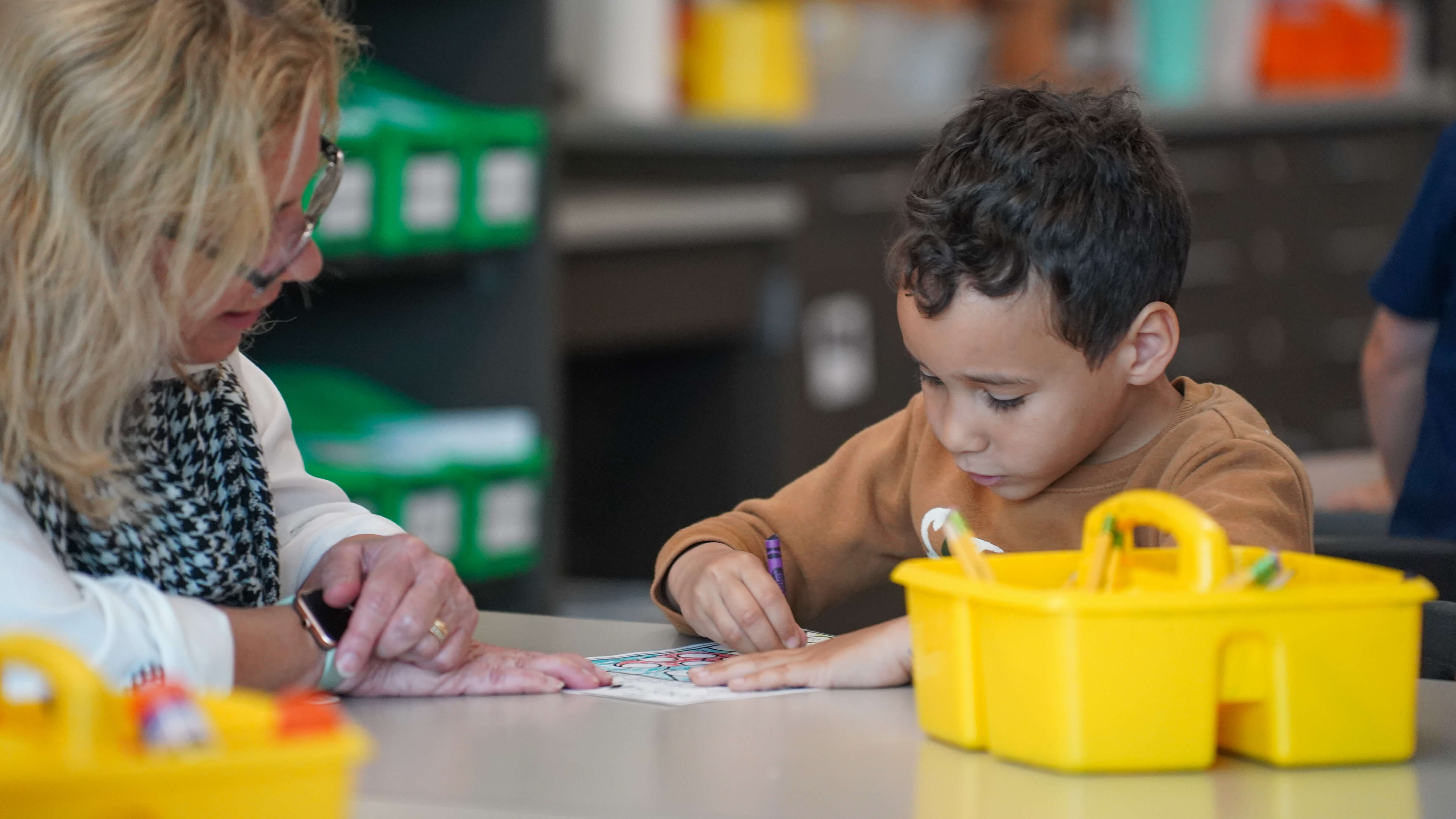 Young student and teacher coloring