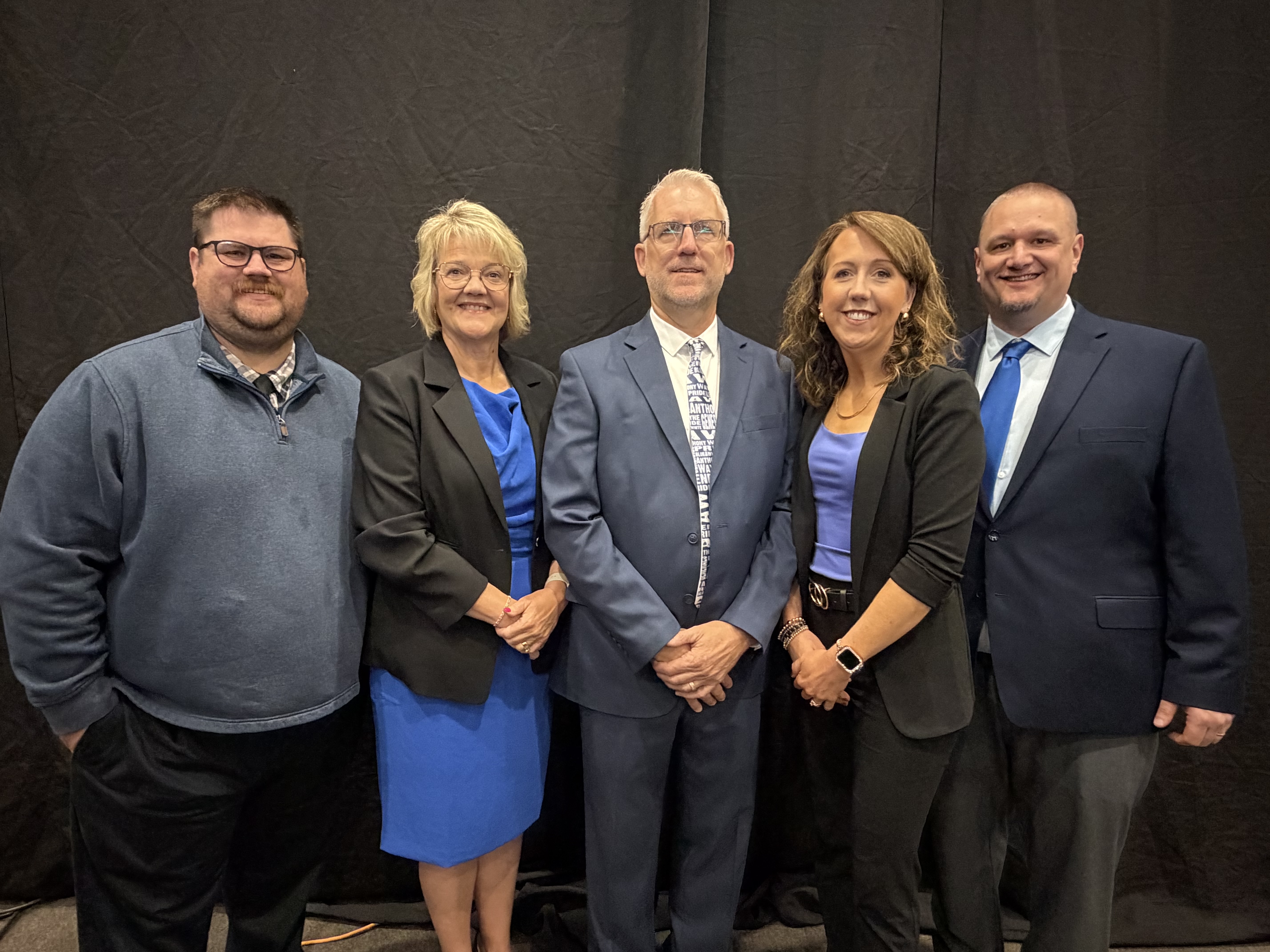 A group of three men and two women in professional clothing