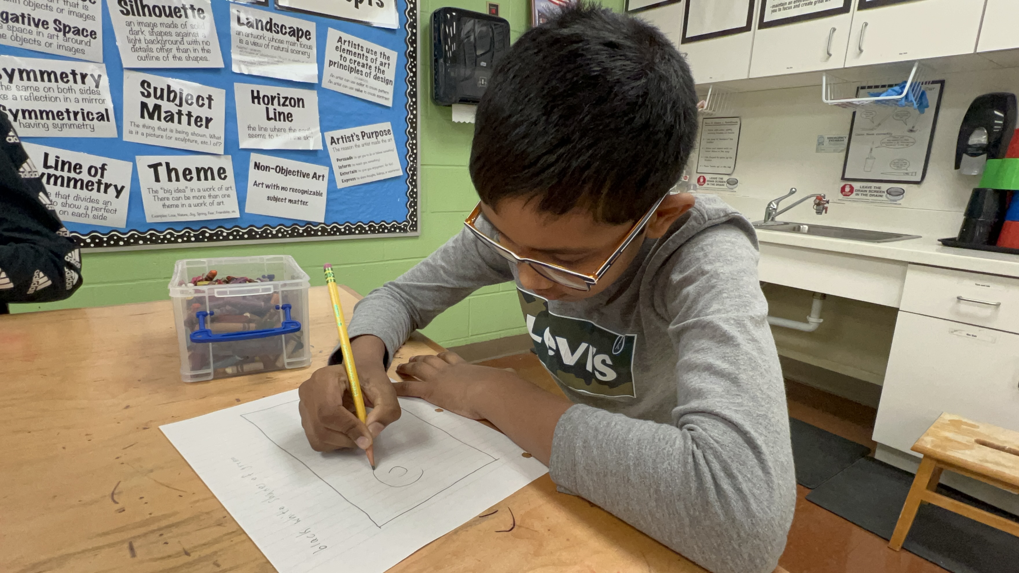 a boy in a gray shirt draws a picture