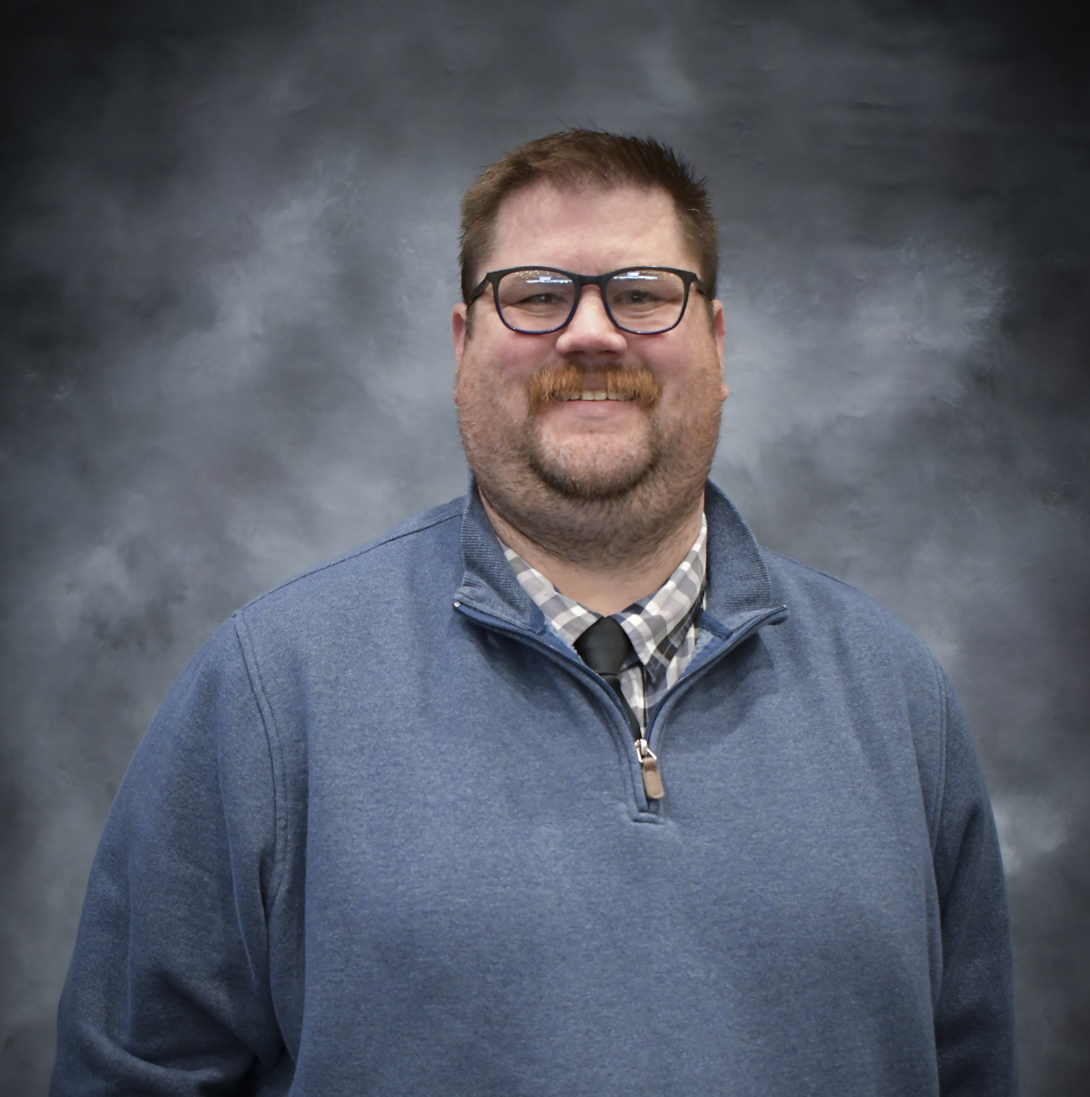 Man in gray sweater and glasses