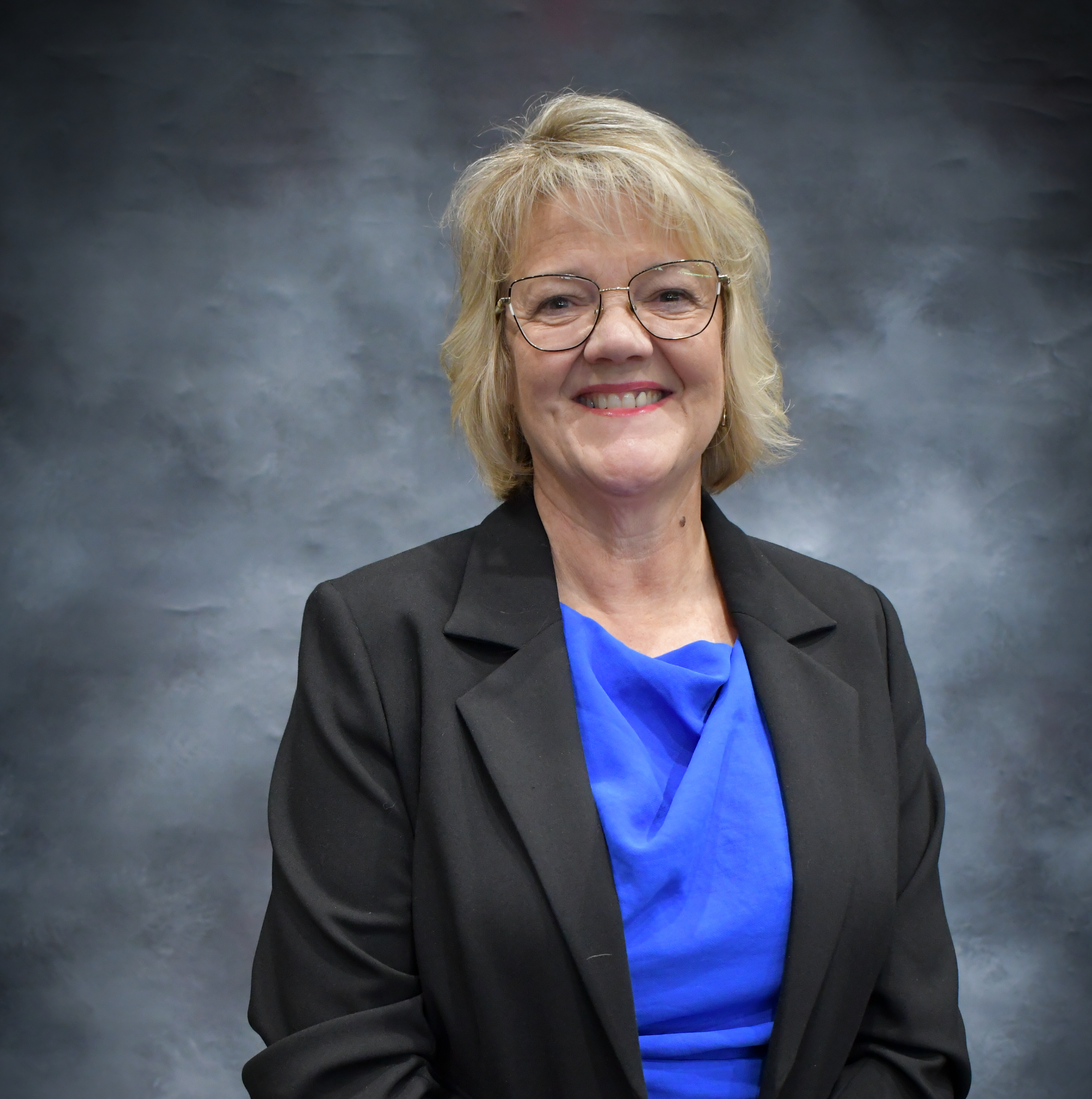 Woman with blonde hair in blue shirt and black blazer