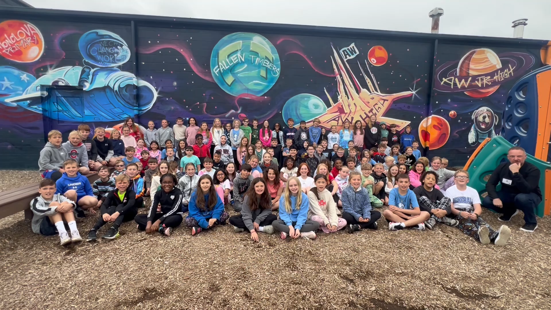 a group of students sits in front of a mural