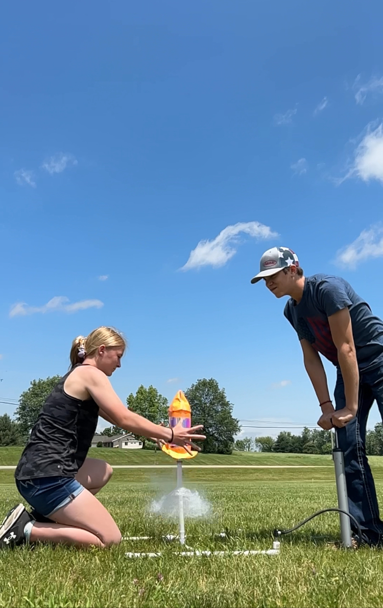 Two students releasing their soda rocket