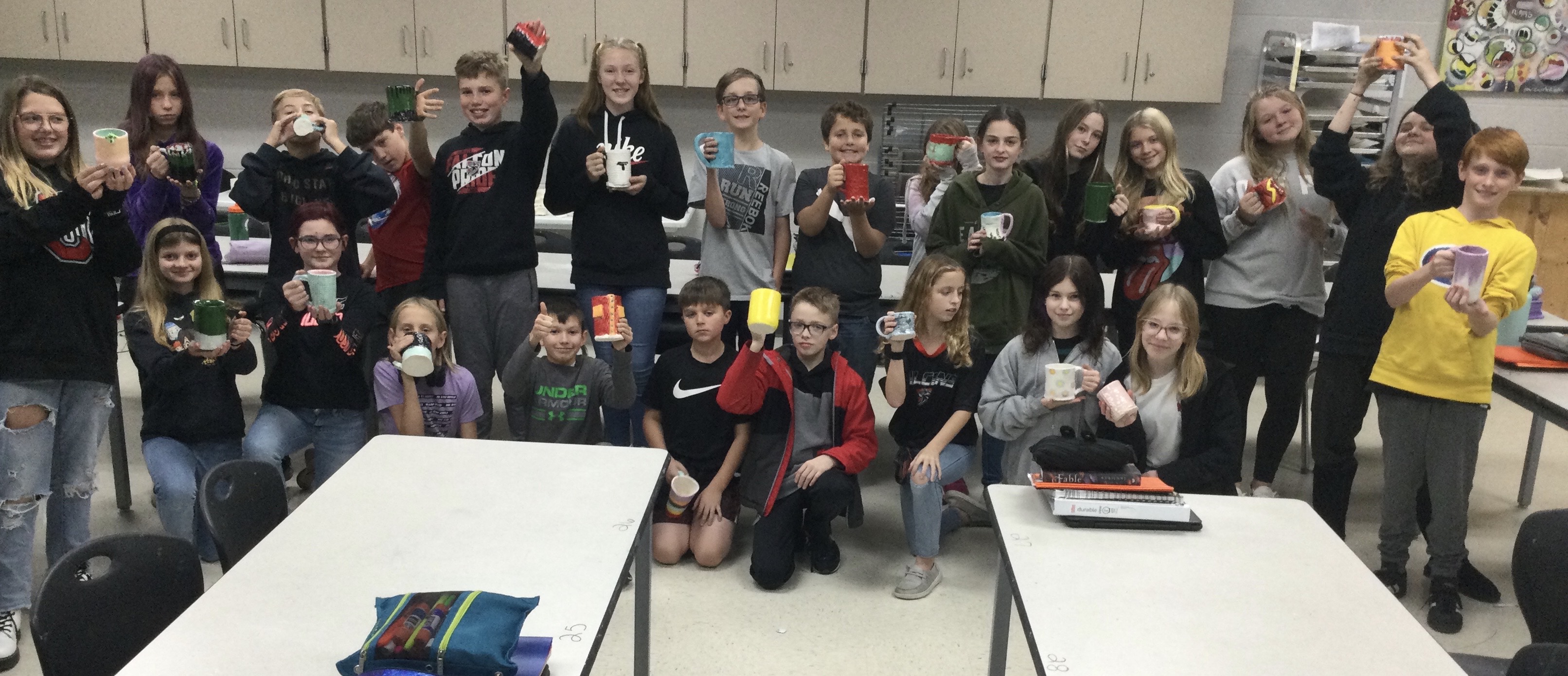 Another classroom photo of students holding their mugs.