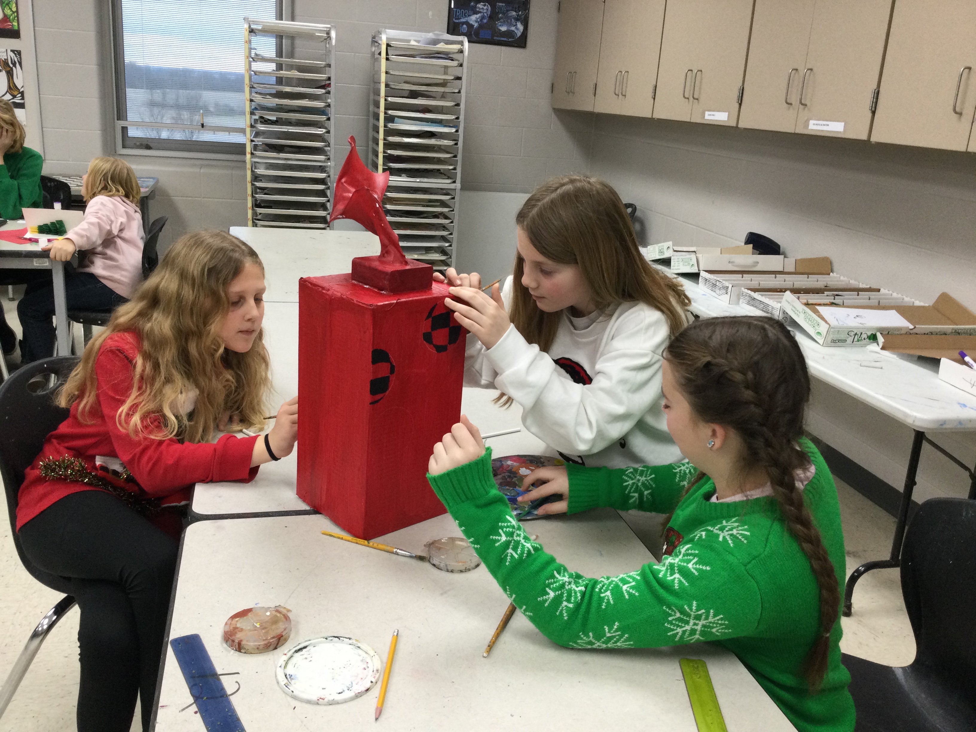Art club students painting a reindeer games trophy.