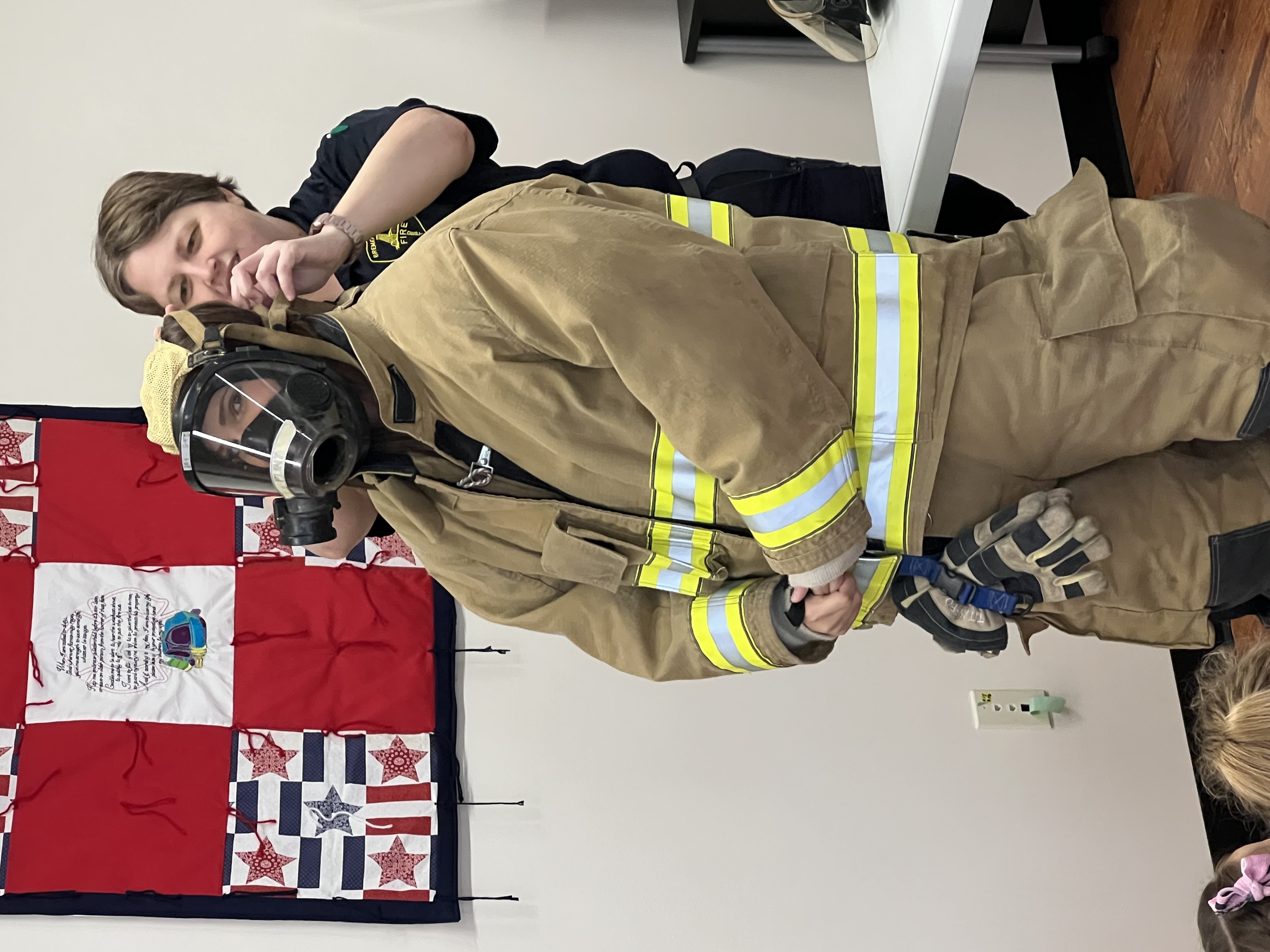 Miss Stewart eyes the camera as a firefighter adjusts her gear.
