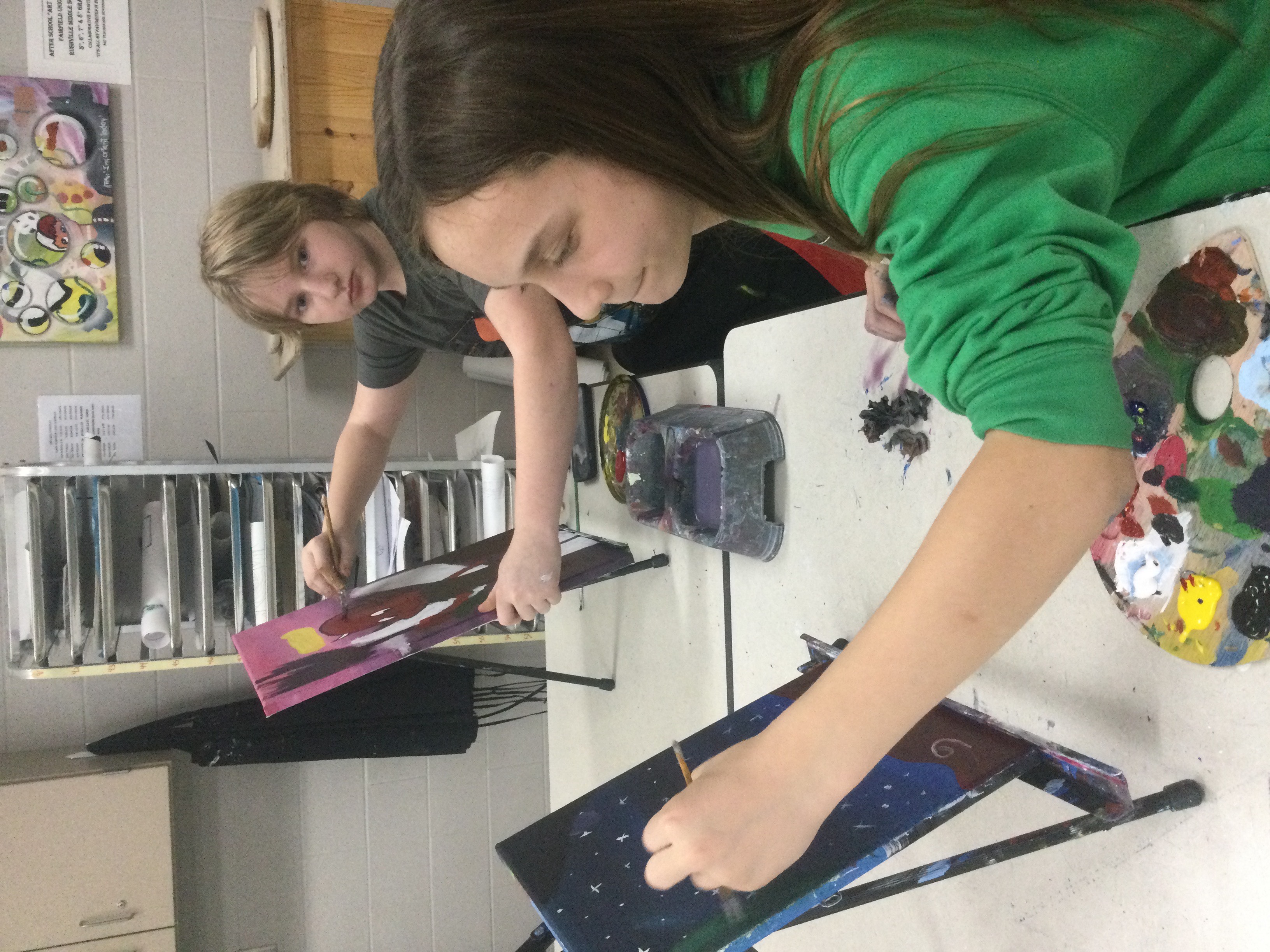 Two students working on their canvas paintings.