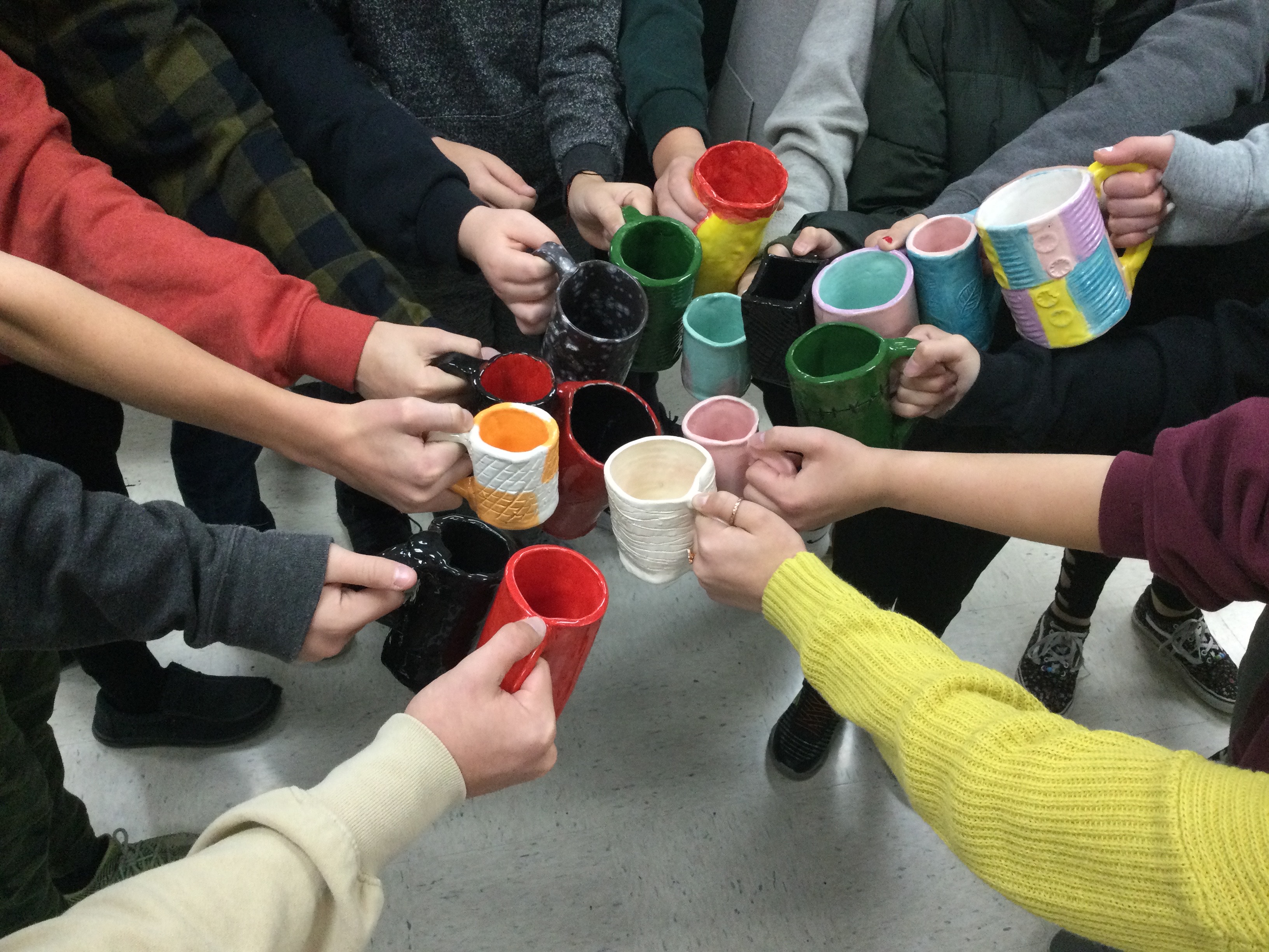 Students making a pinwheel showing off their mugs.