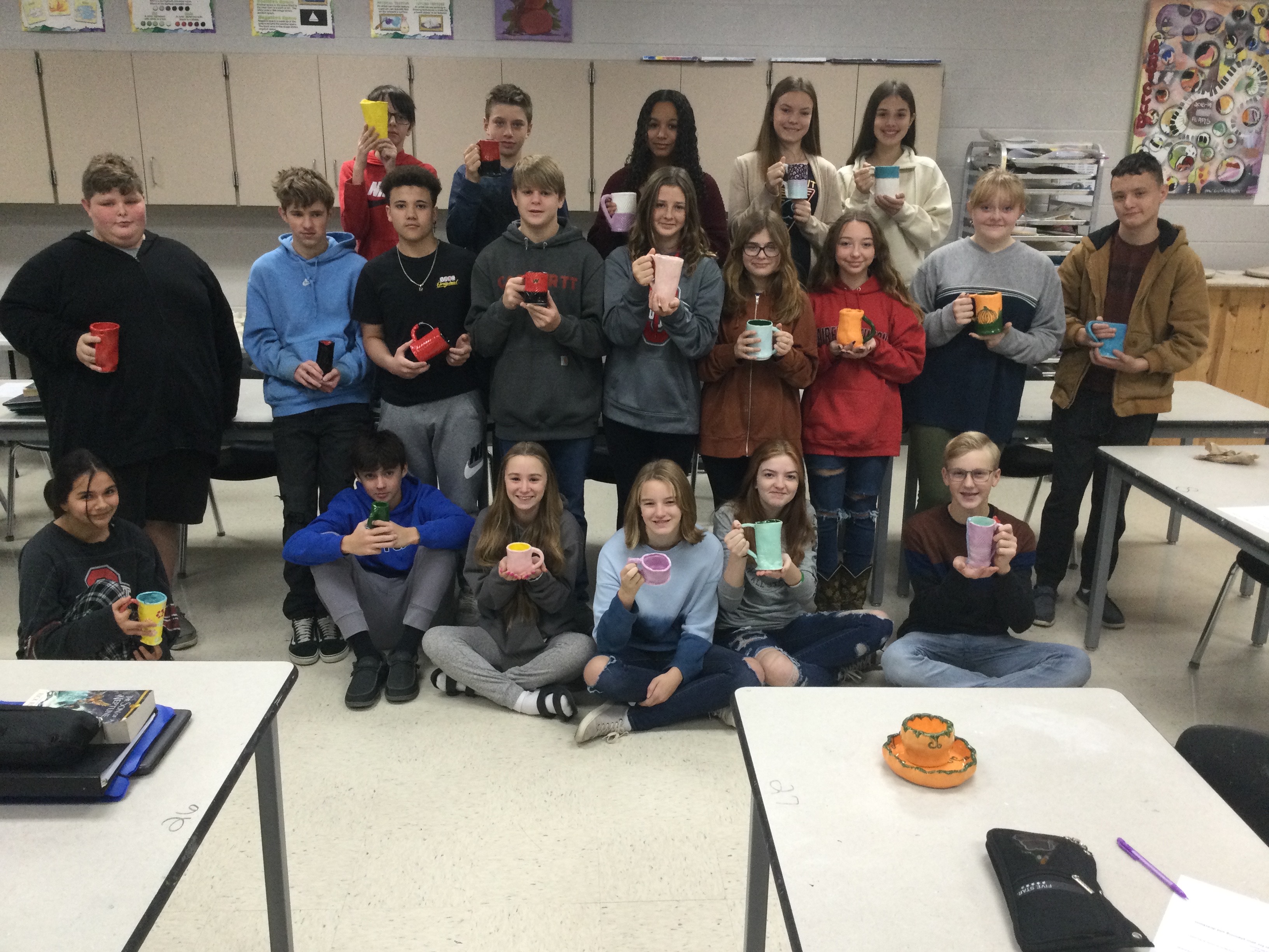 Students pictured in the classroom with their mugs.