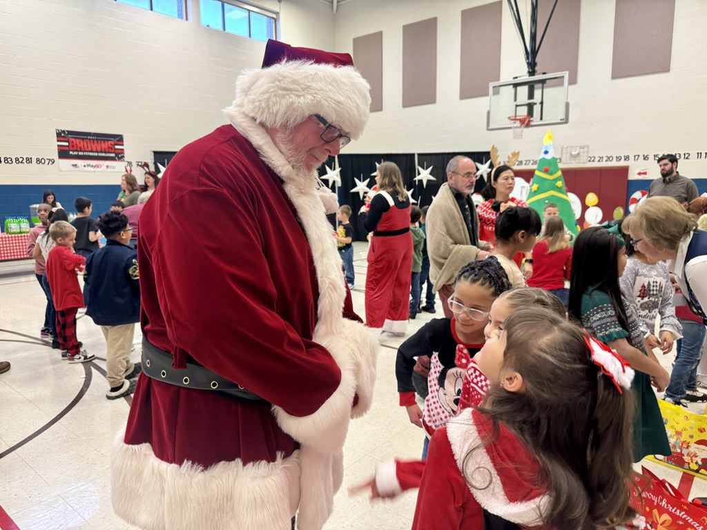 Young kids talk to man in Santa Claus suit.