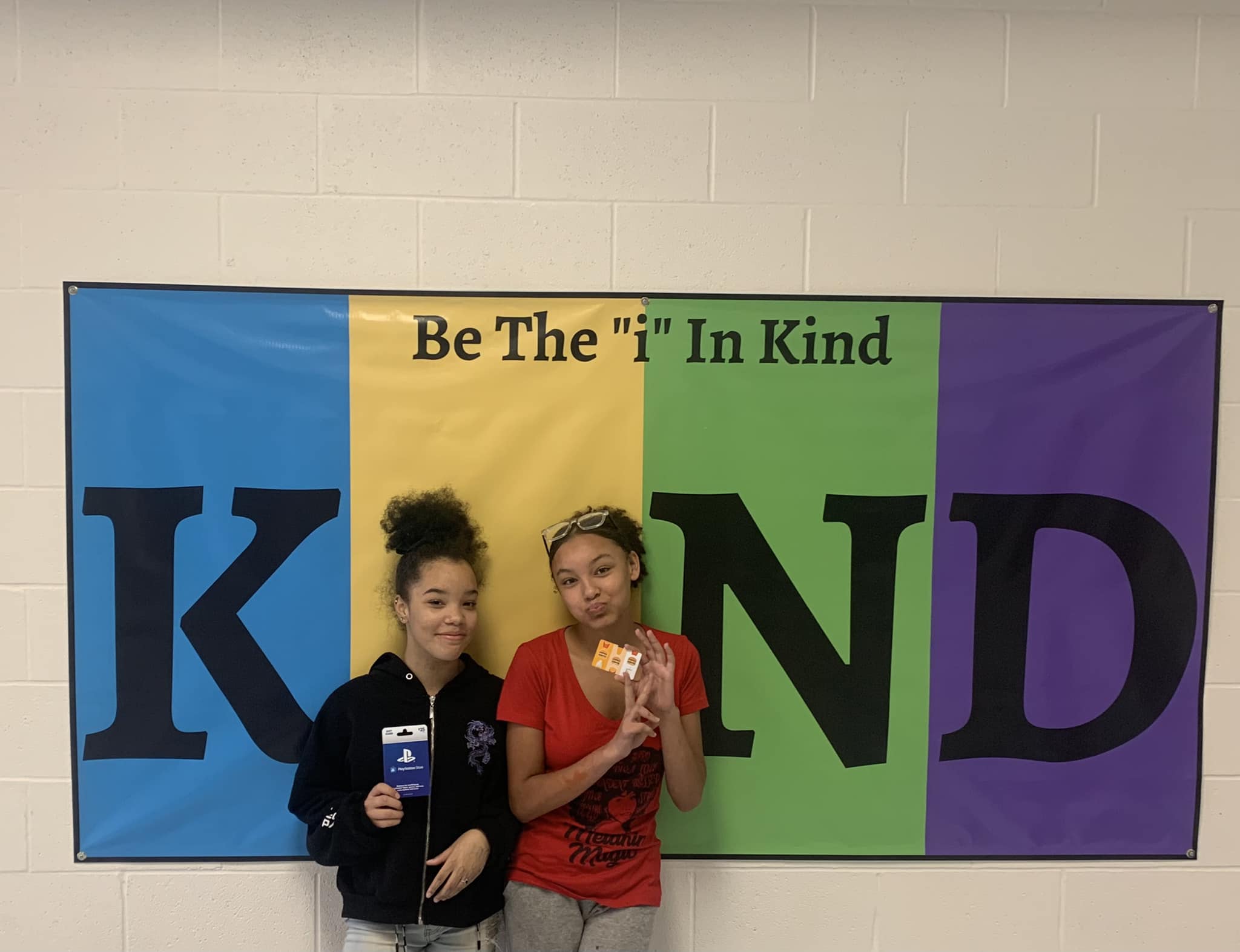 Be The 'i' in Kind poster with two girls standing in front of it