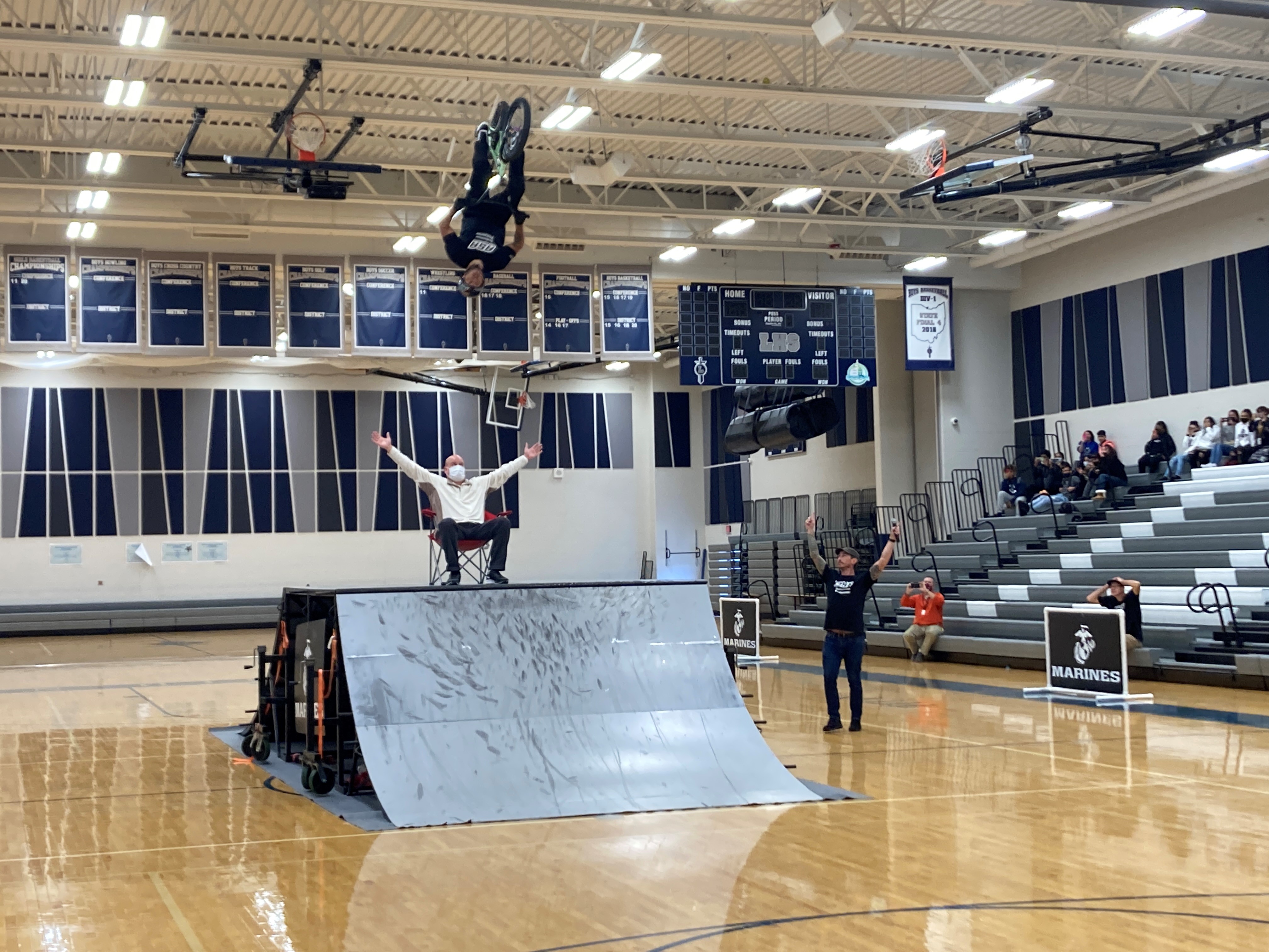 Associate Principal Tim Jama was part of the grand finale. He is sitting in a chair, on top of a bike ramp and a BMX athlete is flipping over this head.